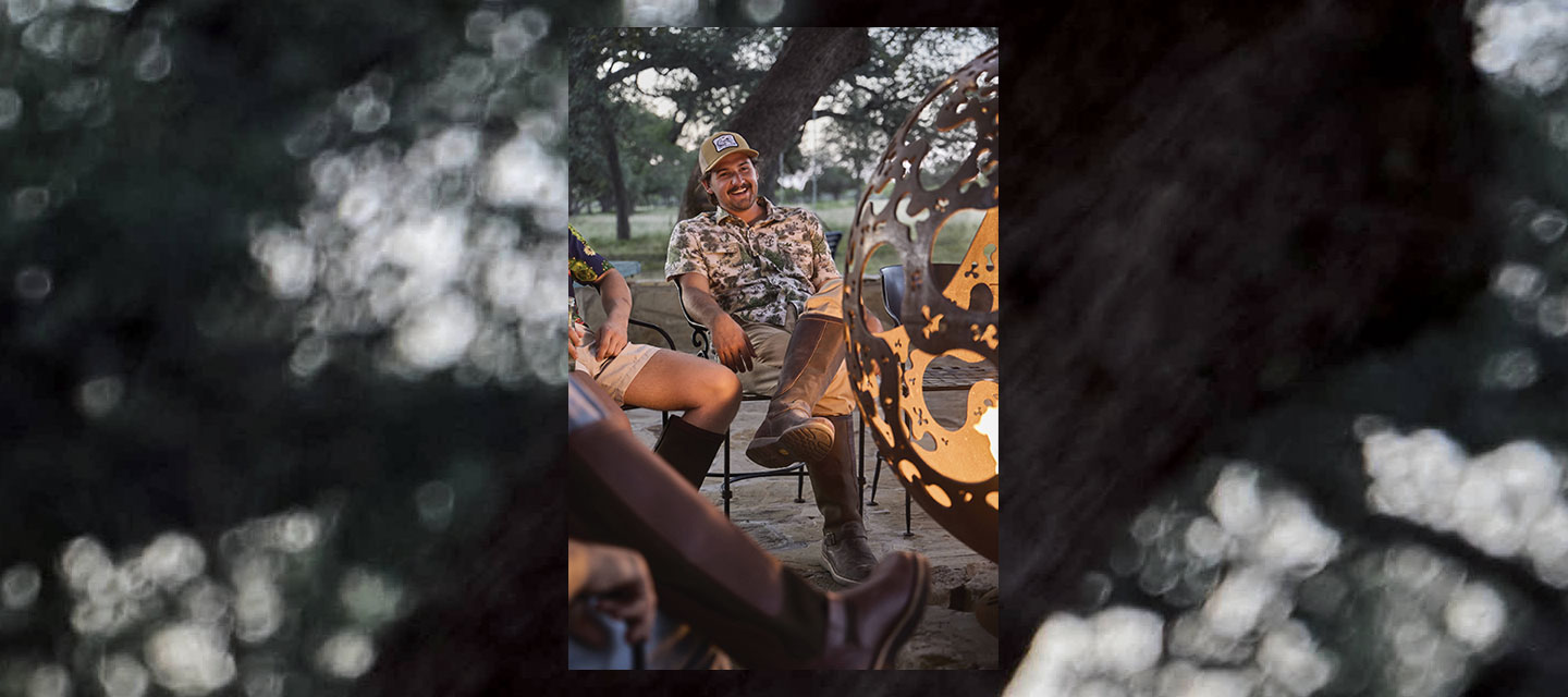 A man wearing Chippewa snake boots by a camp fire.